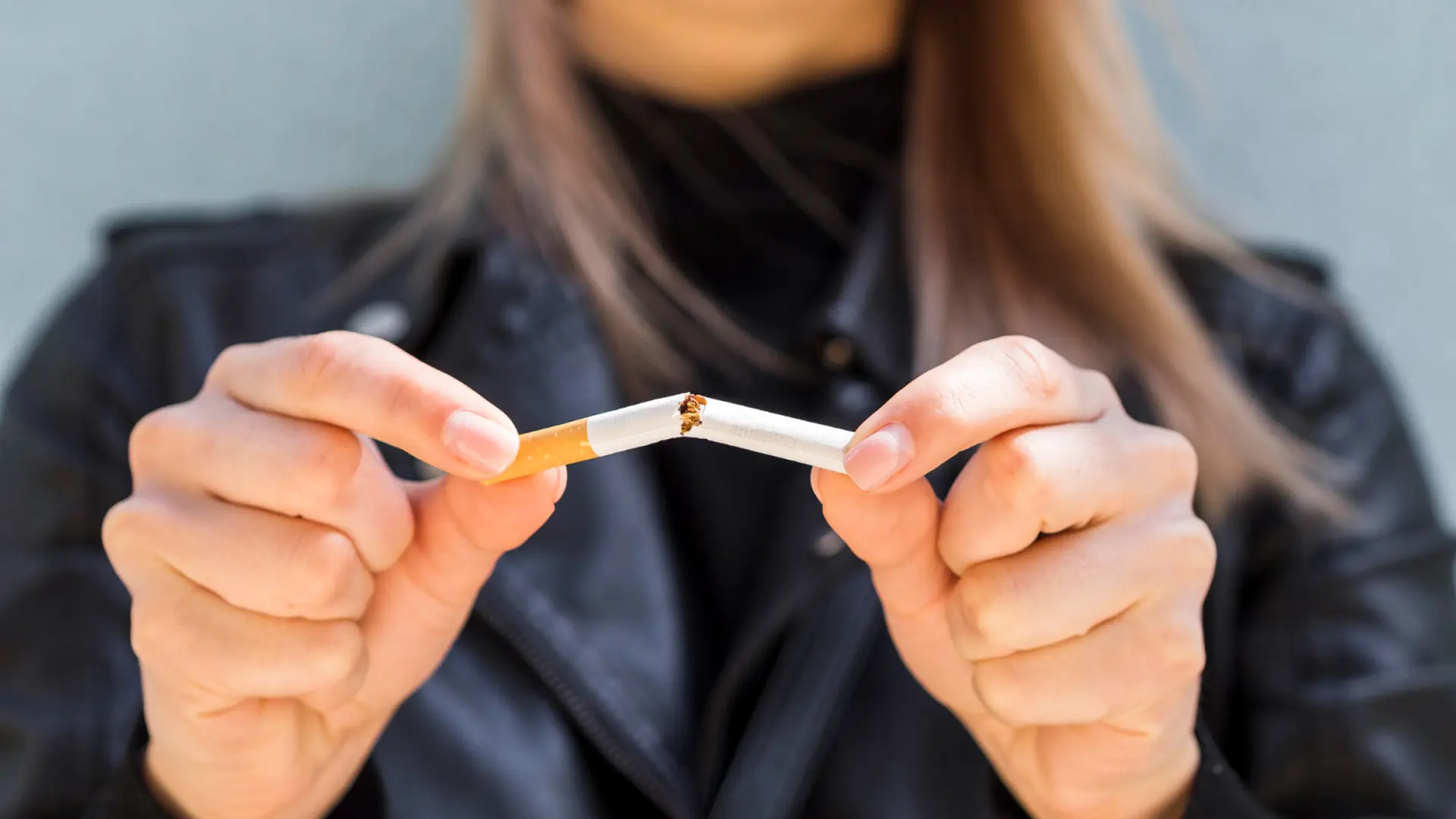 Mulher quebrando um cigarro ao meio