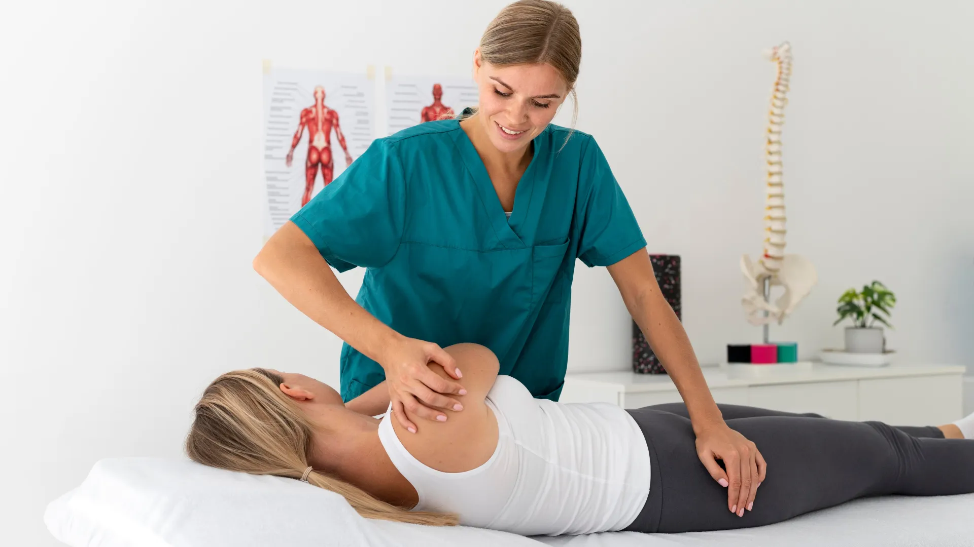 Paciente deitada na cama enquanto médica a ajuda a fazer um movimento com o ombro